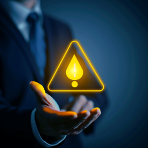 A business professional holding a glowing triangular warning symbol, representing early alerts, risk management, and proactive decision-making.